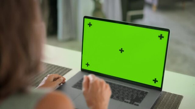 Close up of mock up green screen of modern aluminium laptop on table
