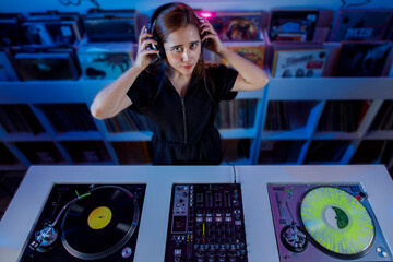 Joven mujer dj latina, mezclando música en una tienda de discos de vinilo. Concepto de música...