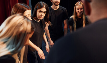 Group of actors in dark colored clothes on rehearsal in the theater - obrazy, fototapety, plakaty