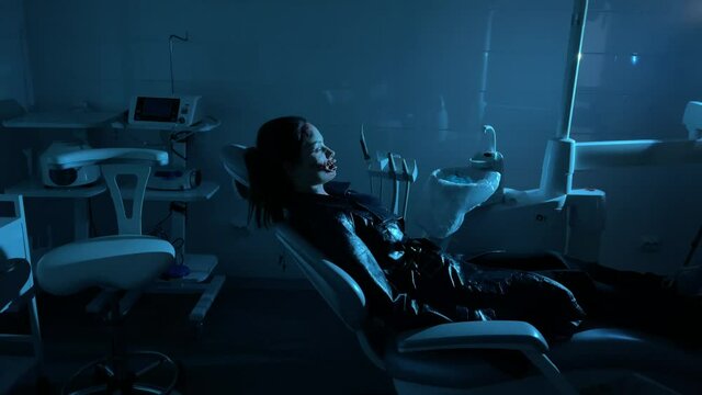 Woman mutant lies in dental chair and raises to a sitting position.