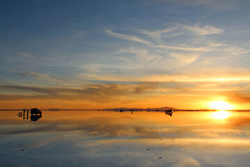 Goldene Stunde zum Sonnenuntergang am Salar de Uyuni in Bolivien mit Spiegelung und Reflektion auf...