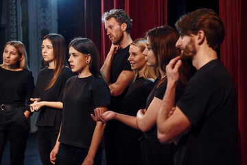 Side view. Group of actors in dark colored clothes on rehearsal in the theater