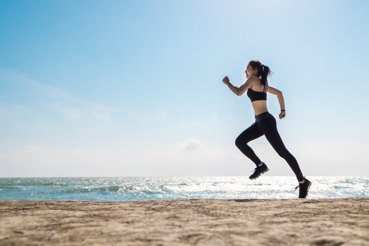 Asian healthy sport athlete girl running or jogging on beach in morning