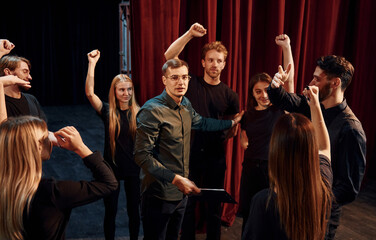 Practice in progress. Group of actors in dark colored clothes on rehearsal in the theater