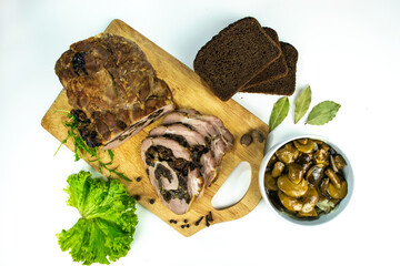 Baked meatloaf pork with prunes and mushrooms cut into pieces on a cutting board.