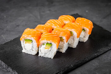 appetizing philadelphia sushi roll with salmon and avocado on a black stone plate