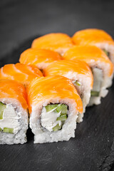 appetizing philadelphia sushi roll with salmon and cucumber on a black stone plate