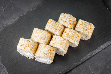 appetizing sushi roll with Philadelphia tofu sesame cheese on a black stone plate