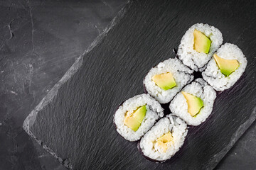 appetizing sushi maki roll avocado on a black stone plate