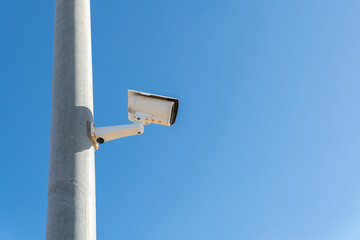 White surveillance camera placed on a metal pole