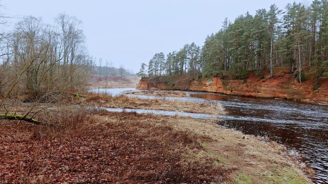 Red sandstone cliffs in the banks of river Salaca during late autumn time, Latvia. Real time drone footage