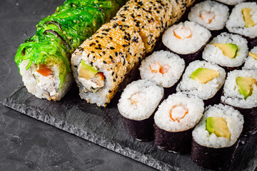 appetizing set of sushi roll on a black stone plate