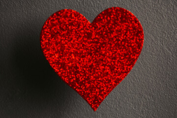 Blurry Sparkle Red Heart on concrete wall background. Photo focus on wall 