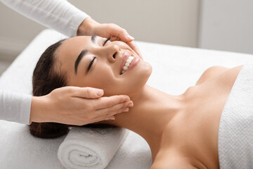 Young Smiling Korean Woman Enjoying Spa Facial Massage In Beauty Salon