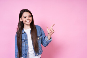 Pretty emotional young girl in a jeans jacket on a pink background.