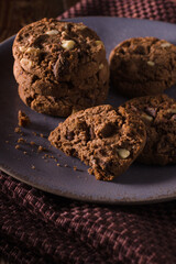 Triple chocolate chip cookies with chunks of white milk and dark chocolate shot with dark creative lighting