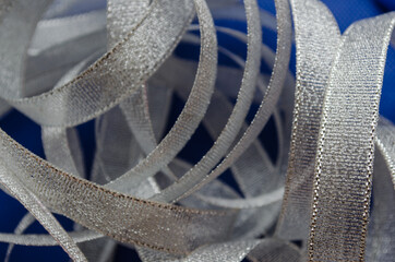 Silver color ribbon isolated blue color.
 A bunch of transparent cotton ribbons with gold trim