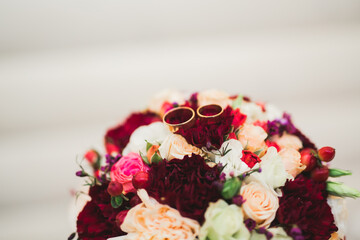 Beautiful toned picture with wedding rings against the background of a bouquet of flowers