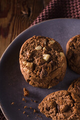 Triple chocolate chip cookies with chunks of white milk and dark chocolate shot with dark creative lighting