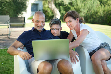 Padre , madre e figlio si divertono a guardare qualcosa di interessante nel computer portatile...