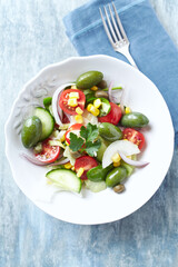 Healthy Salad with Green Olives, Baby Spinach, Cucumber, Cherry Tomatoes and Capers. Bright wooden background. Top view. Close up. 