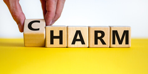 From harm to charm. Male hand turns the cube and changes word 'harm' to 'charm'. Beautiful yellow...