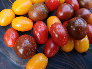 Cherry tomatoes in a spray of water on a dark wooden background. The concept of proper nutrition. Italian cuisine. Copy space. Flat layout. Top view.