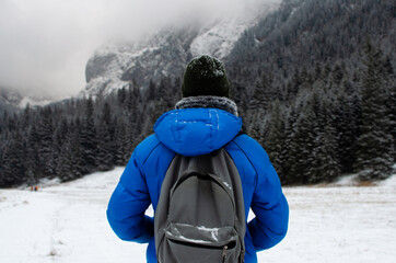 Man hiking with backpack, foggy winter mountains 