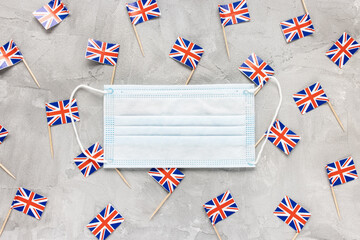 White medical mouth masks and United Kingdom flags on gray background. Coronavirus Covid-19...