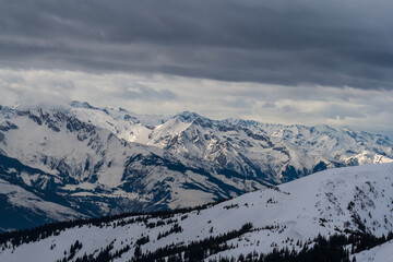 Obraz premium View of the snow-capped mountains in the Schmitten ski area in Zell am See. In the background is a beautiful sky with clouds.