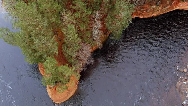 Red sandstone cliffs in the banks of river Salaca during late autumn time, Latvia. Real time drone footage