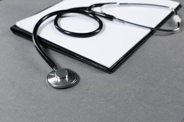 Stethoscope and tablet for recording patients on gray background