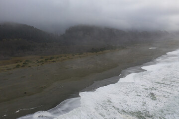 The marine layer drifts over a scenic beach in Klamath, Northern California. This incredible region is home to the world's most beautiful temperate forests. Redwood trees are common here.