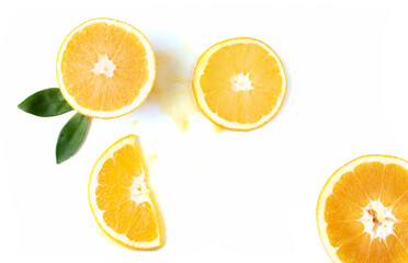 Obraz premium Orange slices with green leaves and spilled orange juice on a white background.