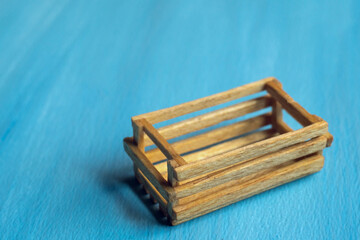 Miniature wooden box for vegetables and fruits, made of matches. On the blue isolate, a place for the inscription.