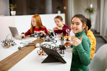 Happy kids programming electric toys and robots at robotics classroom