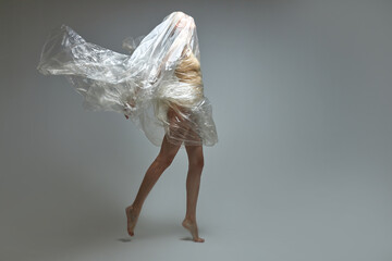 side view on female in a plastic bag, breaking free from plastic trash, showing the concept of irresponsibility of people to nature and the environment