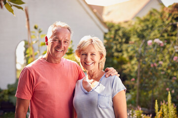 Portrait Of Loving Retired Couple Working In And Enjoying Summer Garden At Home