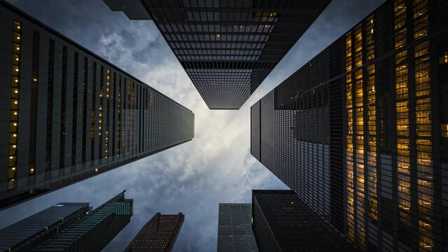 Business and finance concept, moody time lapse view looking up at modern high rise office buildings at dusk in the financial district of Toronto, Ontario, Canada, zoom out.