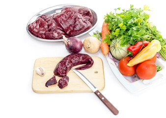 Raw liver and vegetables on a table close-up