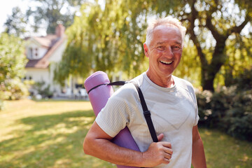 Portrait Of Senior Man At Home In Garden Wearing Fitness Clothing Ready For Outdoor Yoga Session