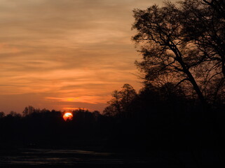 Sunrise over the river, sunrise over the river, contour of trees against the background of the rising sun