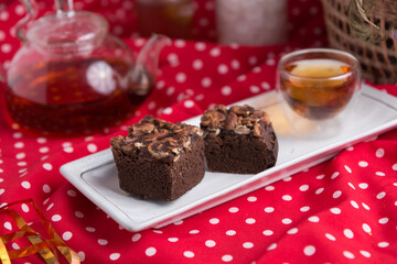 Tea pot and tea cup on wood table with honey and suagr in mag with flower basket on red cloth napkin, with butter cookies and brownies