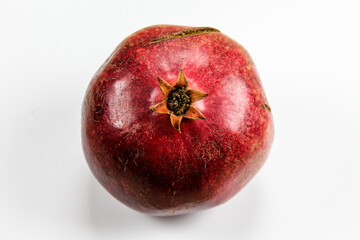 Red ripe pomegranate fruit against a white background. Anthers on ripe fruit up close. Rind outer skin of pomegranate. Macro of pomegranate fruit. Picture from top to bottom.