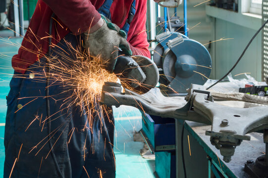 The car mechanic uses an angle grinder to process the frame - Powered by Adobe