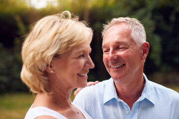 Portrait Of Laughing Senior Couple In Garden At Home Together