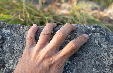 Old man's hand gesture on the stone surface