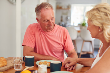 Senior Woman Comforting Man Suffering With Depression At Breakfast Table At Home