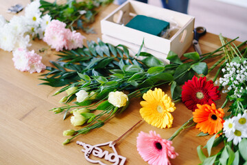 Flat lay composition with florist equipment and many flowers on wooden background