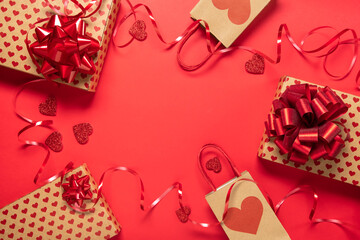 Festive composition with gift box and hearts on red background. Top view, copy space. Valentine's day concept.